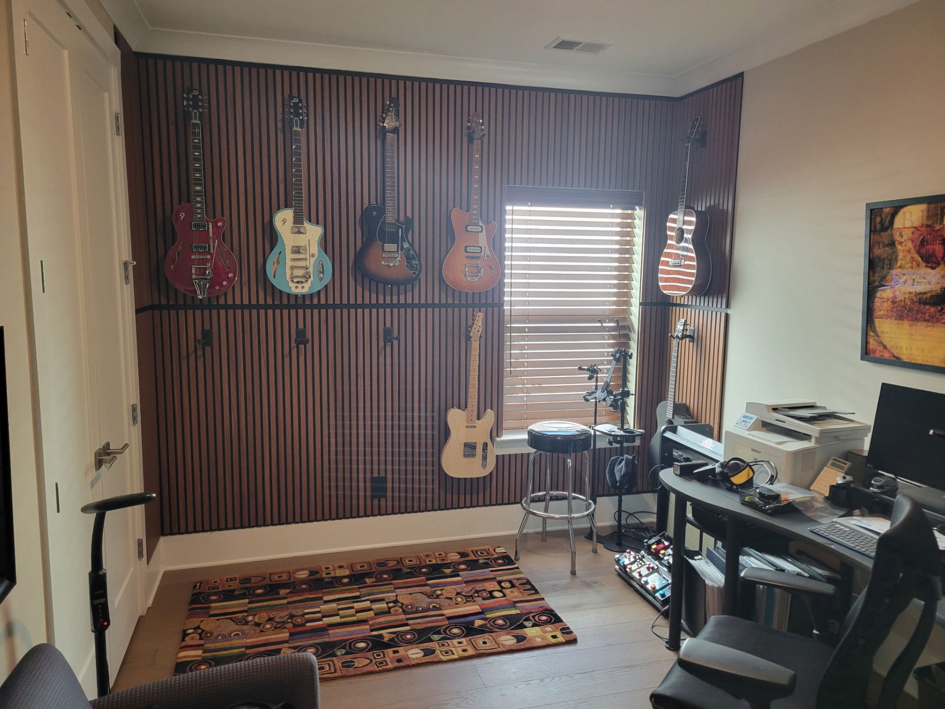 Finished floor-to-ceiling wood slat accent wall in a home music studio