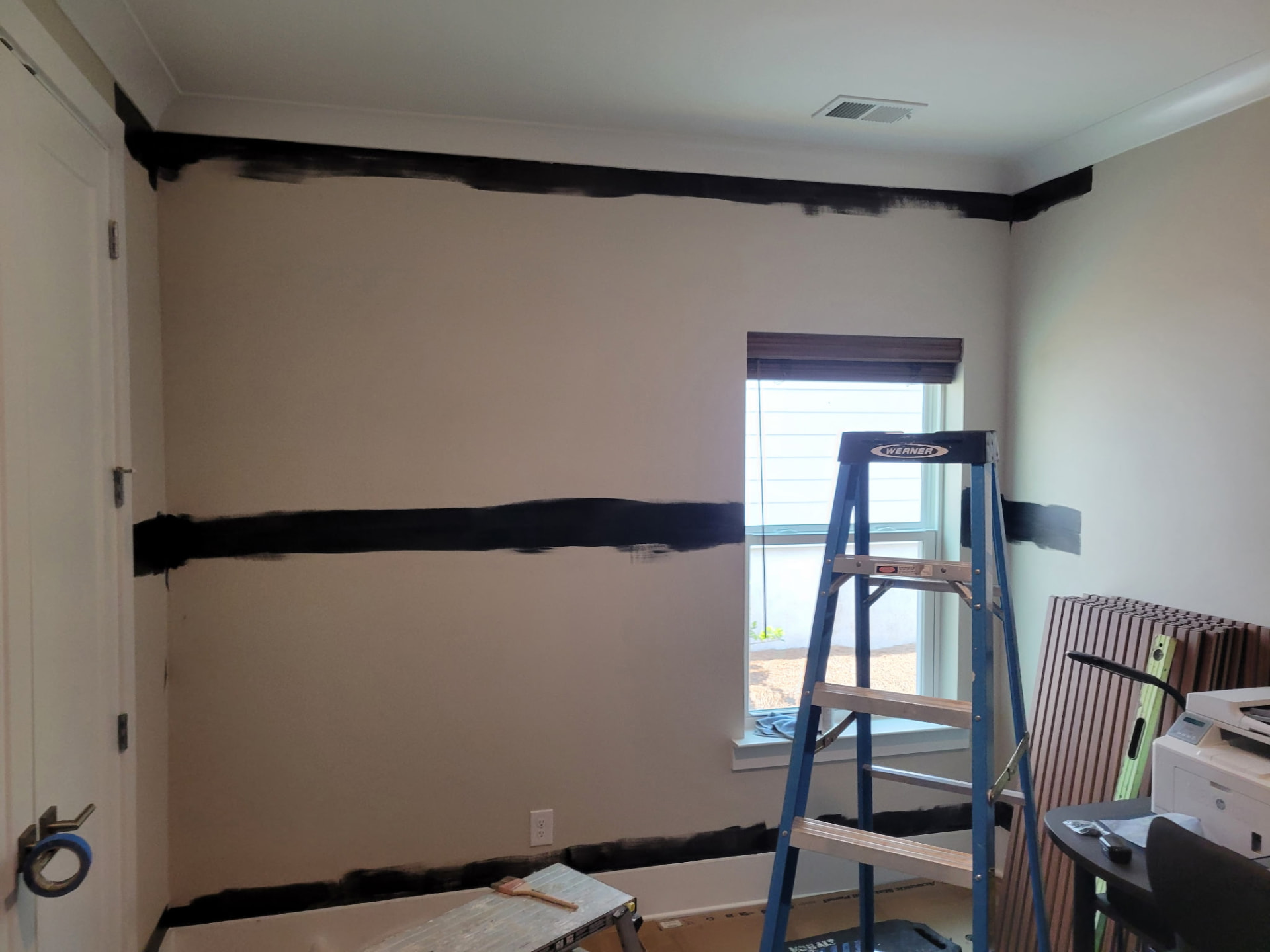 Plain painted room wall marked out in black paint before slat panelling