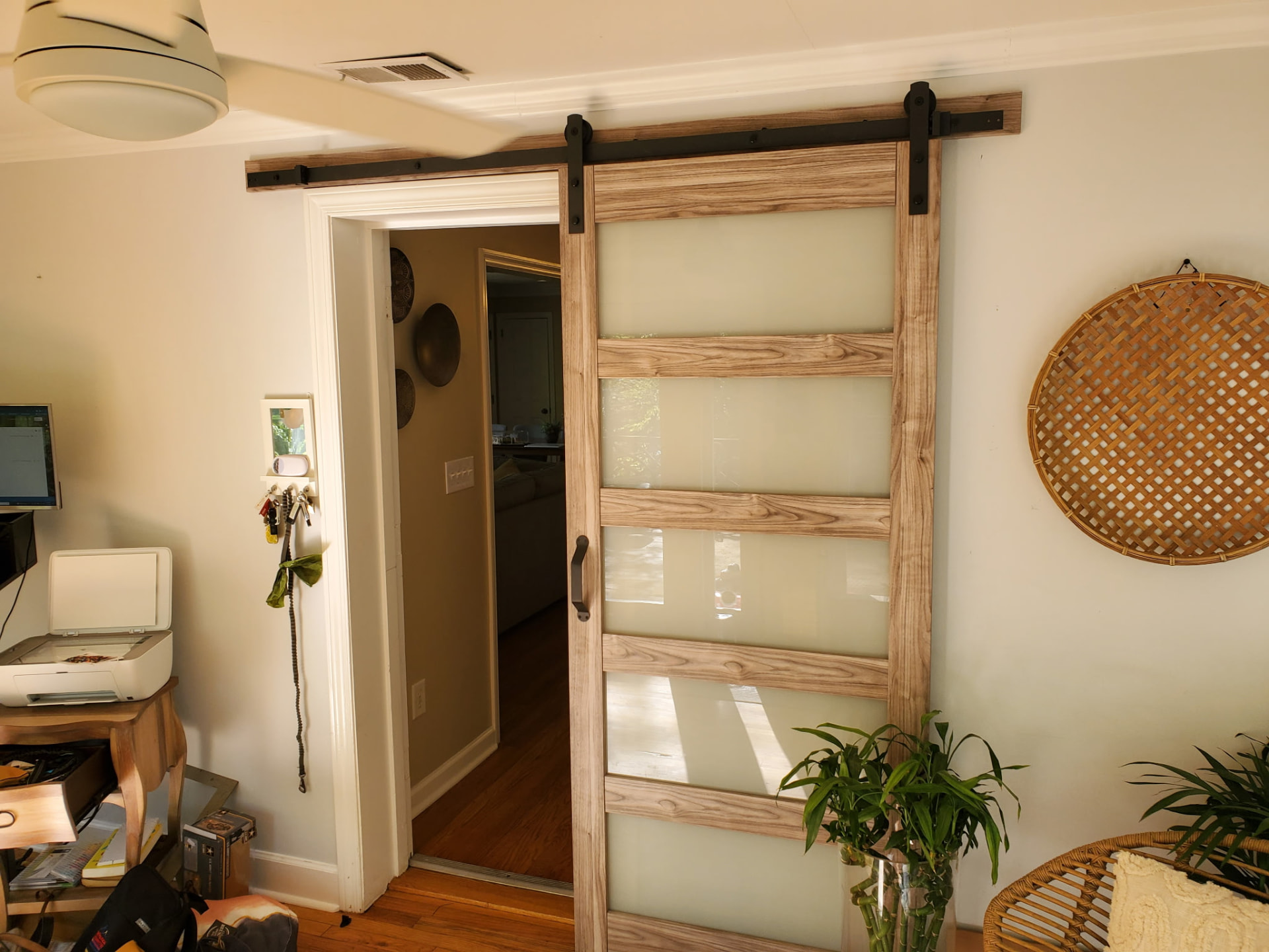 Sliding barn door with frosted glass panels on black steel track in a home office